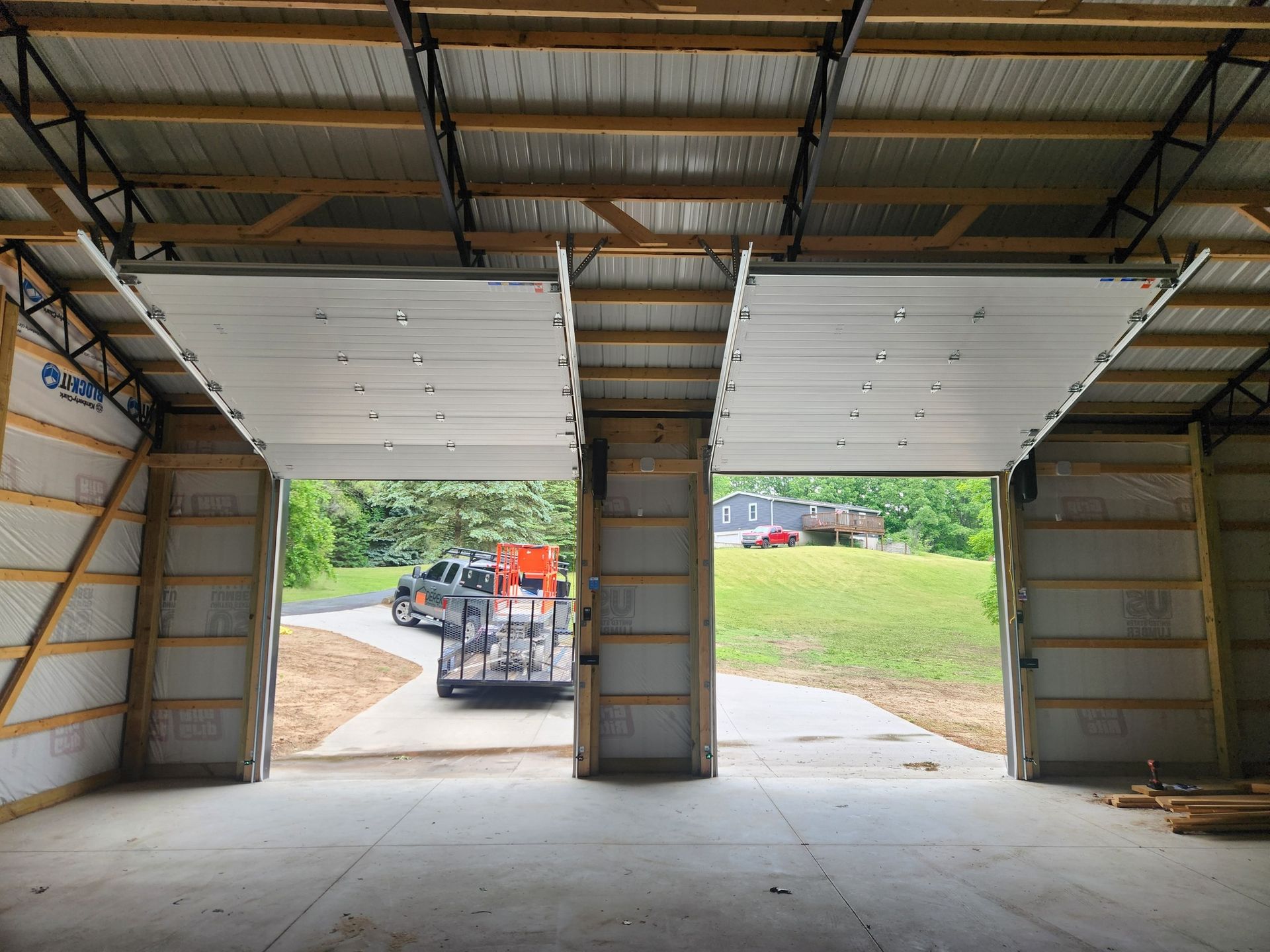 A car is parked in a garage with the doors open.