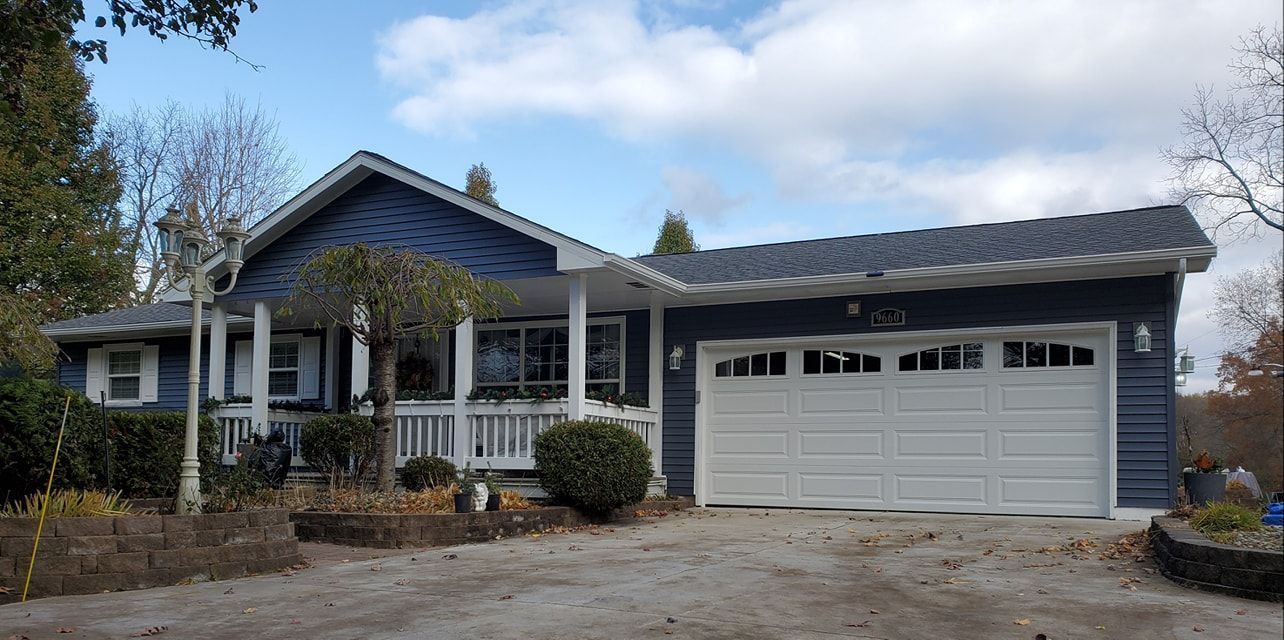 A blue house with a white garage door and a porch.