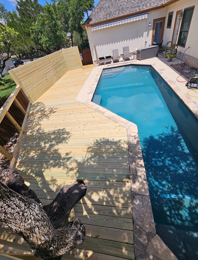 A large swimming pool is surrounded by a wooden deck.