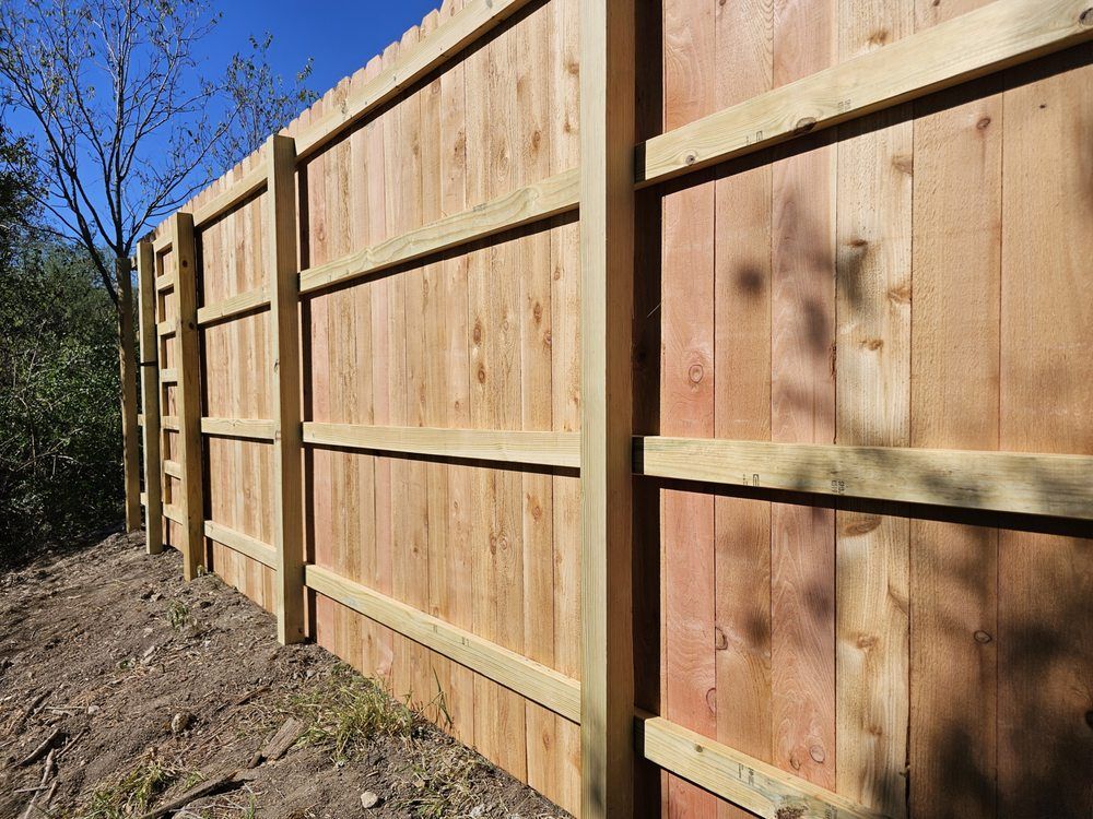 Wooden fence, cedar colored planks, with horizontal support beams.
