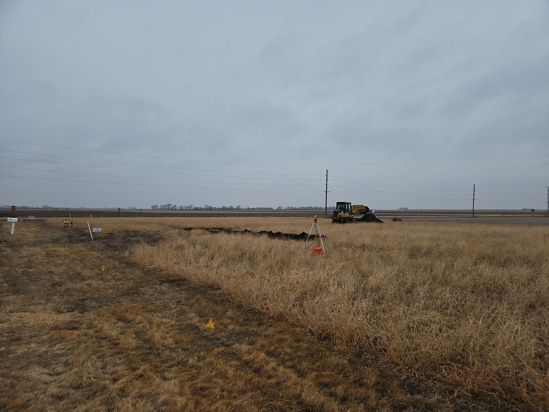 A large dry grass field with a bulldozer in the background.