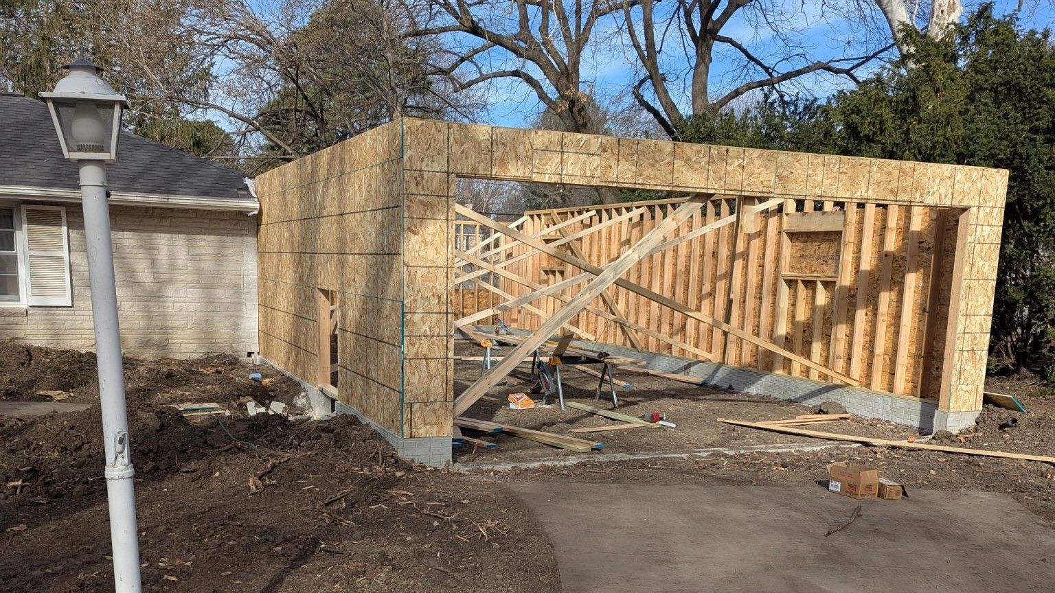 A wooden garage is being built in front of a house.