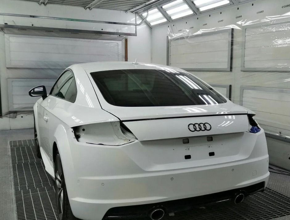 Audi coupé bianca in un garage, vista posteriore con fanali posteriori e bagagliaio danneggiati.