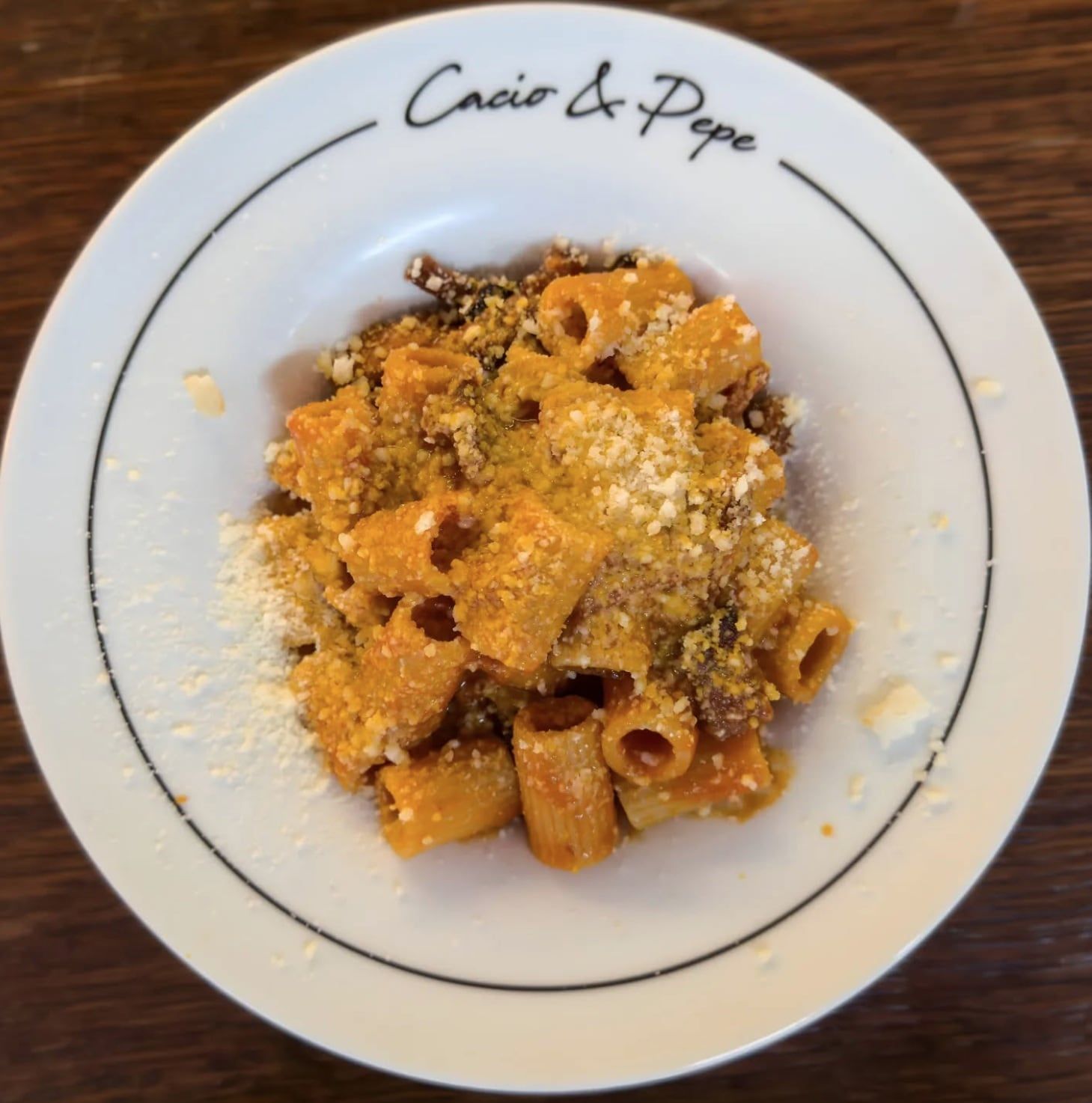 Piatto di pasta in una ciotola bianca con la scritta "Cacio e Pepe".