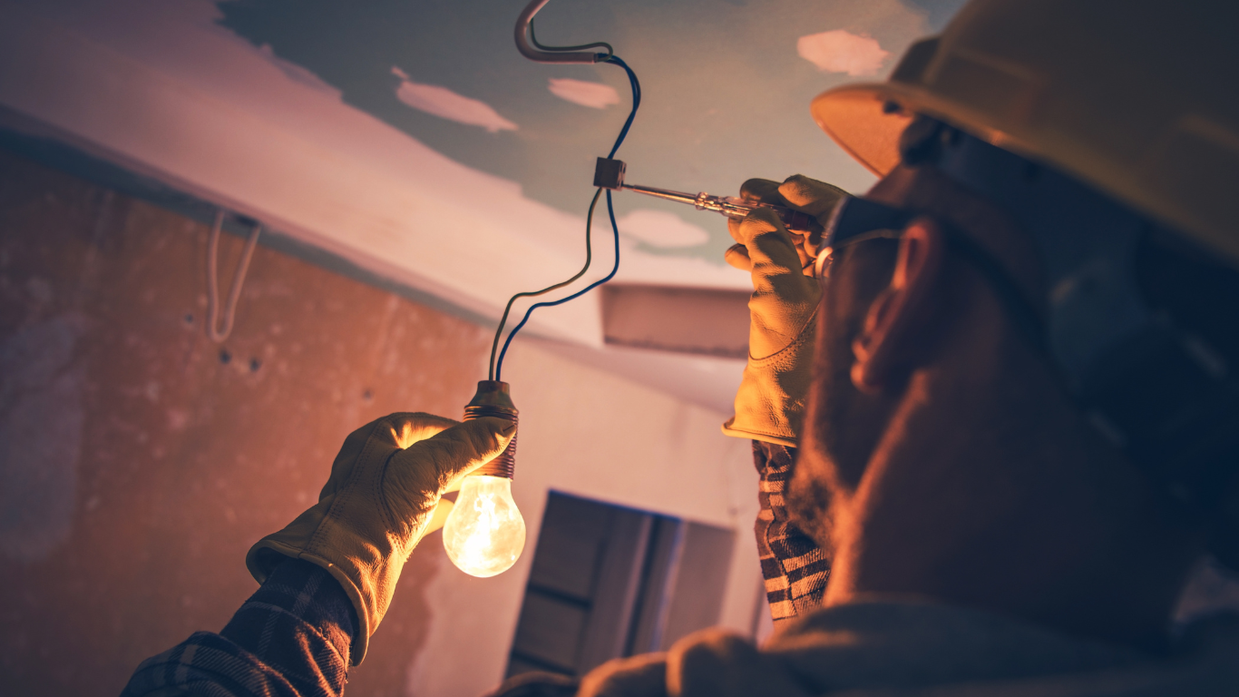 An electrical contractor is holding a light bulb in his hand.
