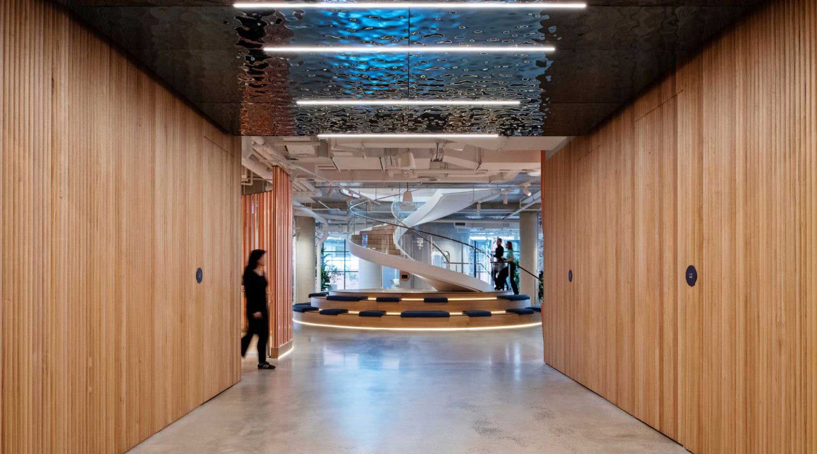 A Woman Is Walking Down A Hallway In An Office Building