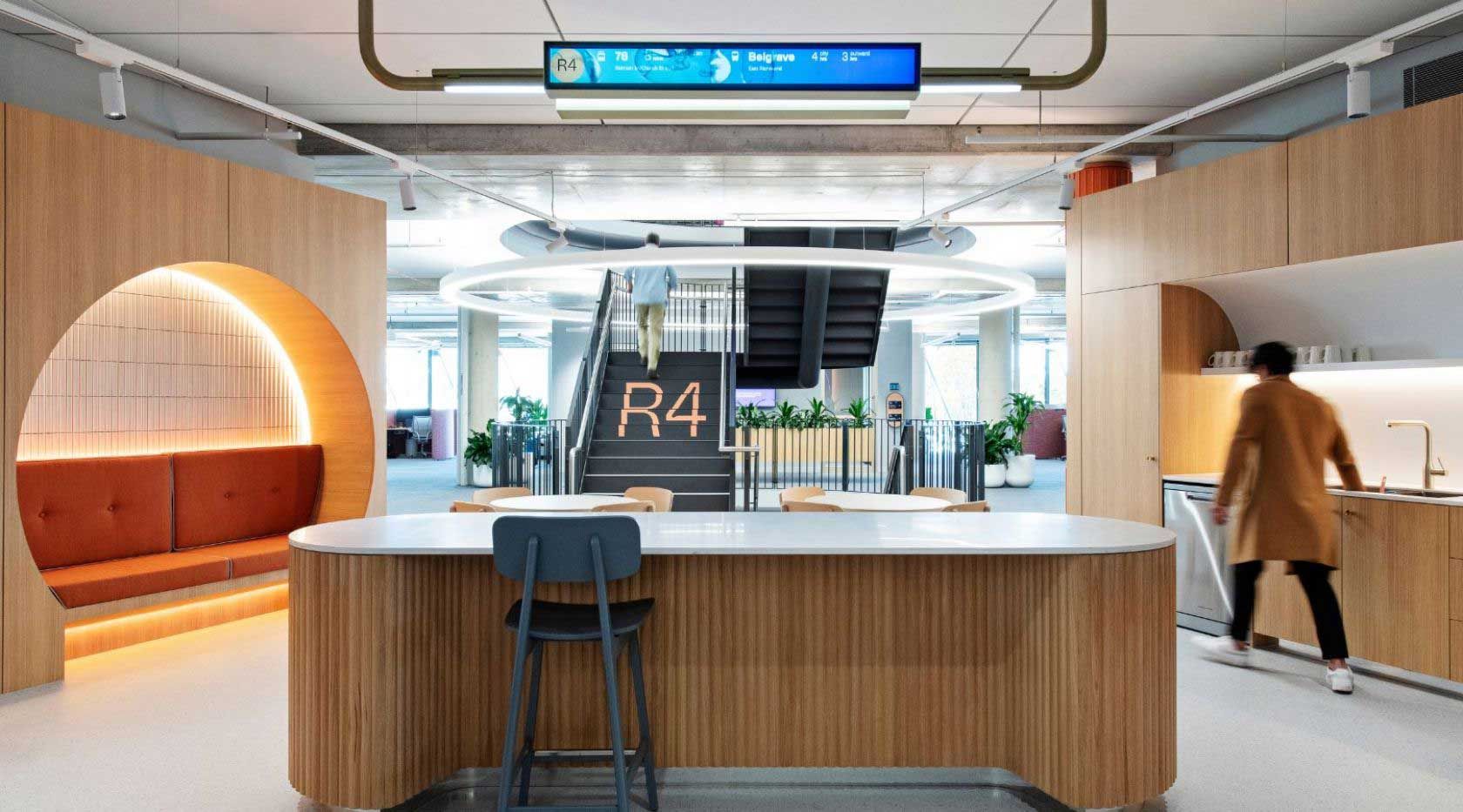 A Woman Is Standing At A Counter In A Kitchen In An Office Building