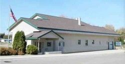 A small white building with a brown roof and a flag on top of it.