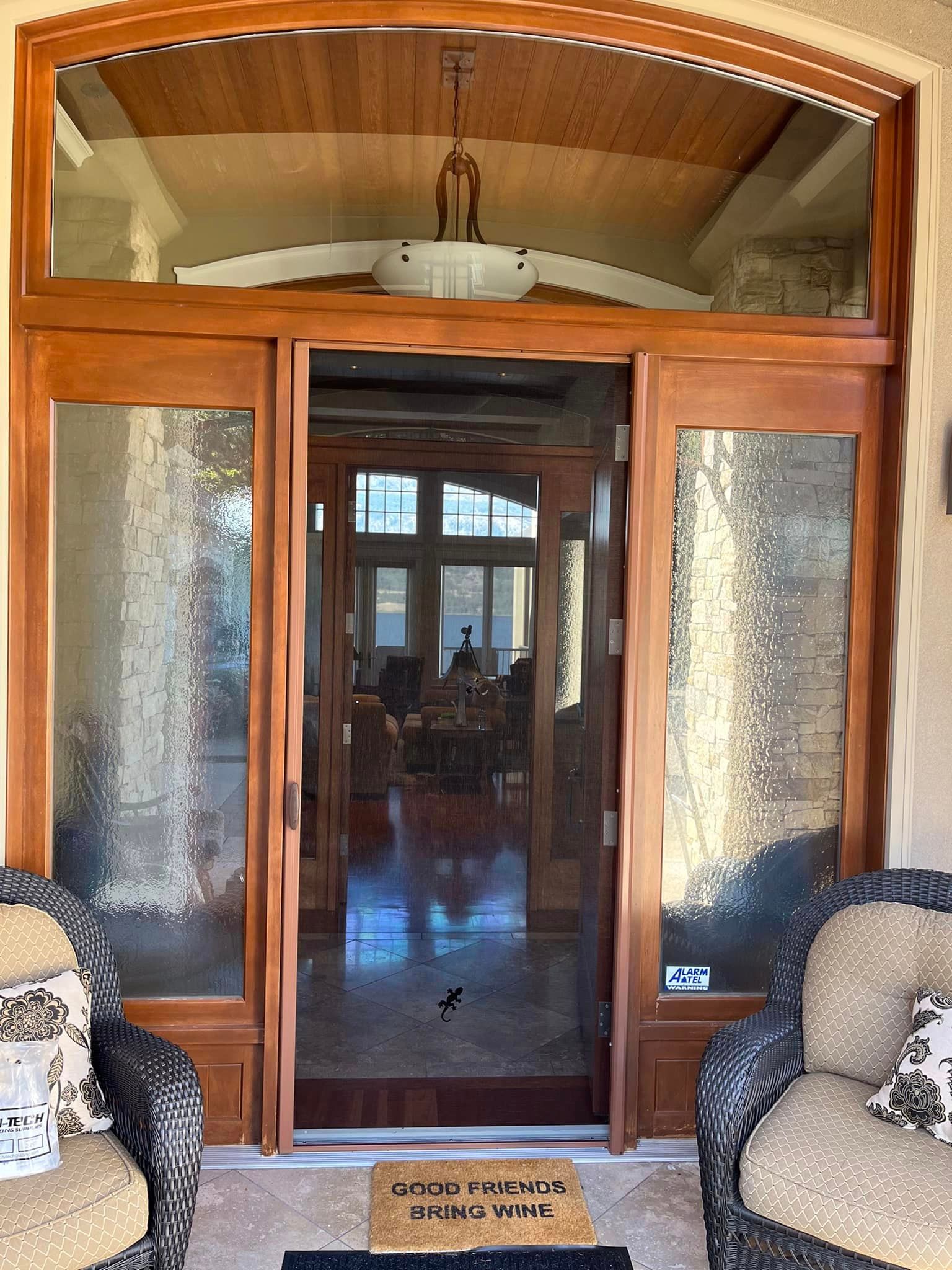 Wooden double doors with frosted glass panels and an arched transom leading into a living room
