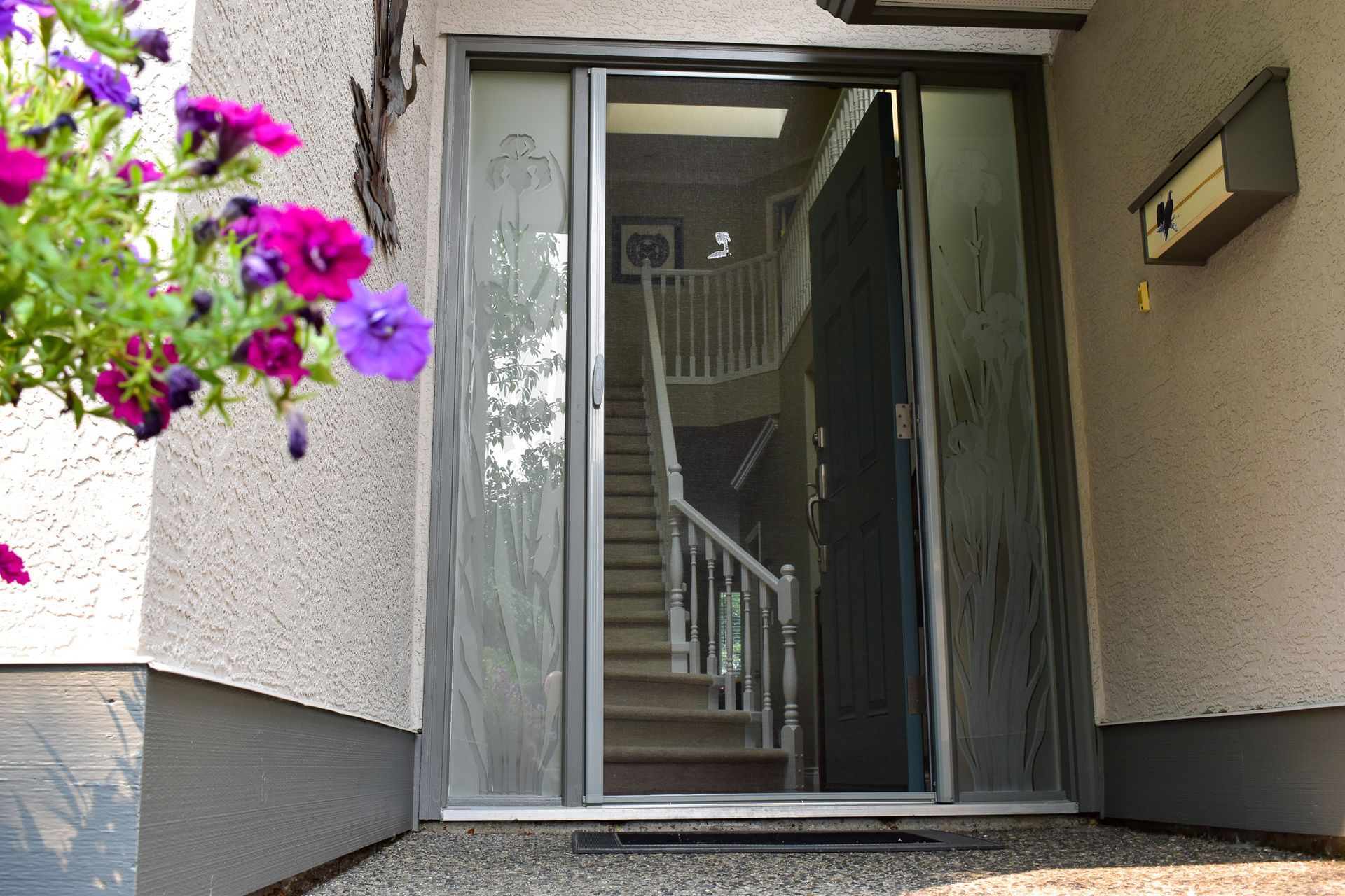 Front entrance with open glass door, staircase visible inside, and purple flowers hanging at left.