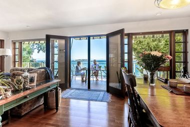 Bright living room with open doors to a seaside patio and ocean view