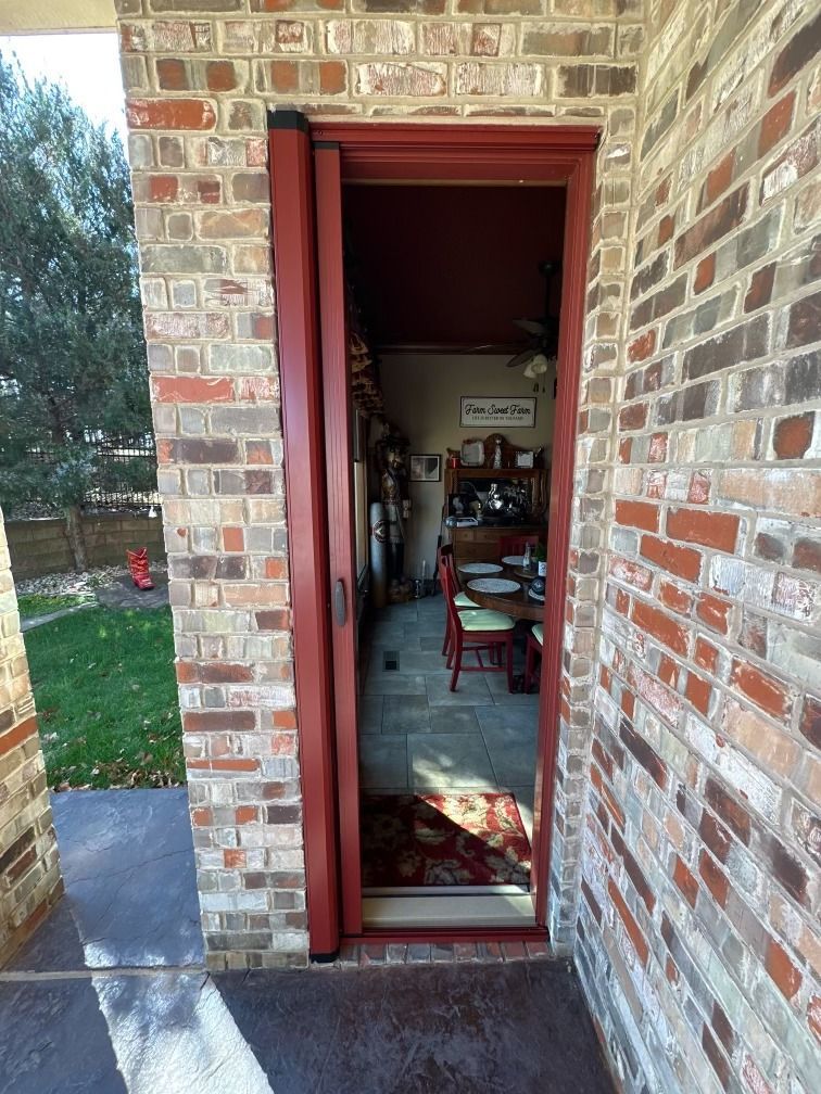 Open brick doorway leading into a dim room with furniture, viewed from a porch.