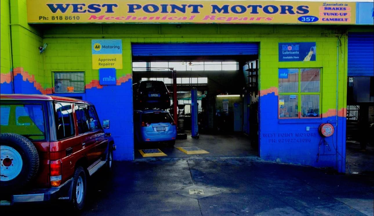 West Point Motors auto shop with vehicles inside, open garage entrance, blue and green exterior.