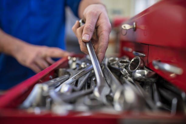 A person's hand reaching into a red toolbox filled with various wrenches.
