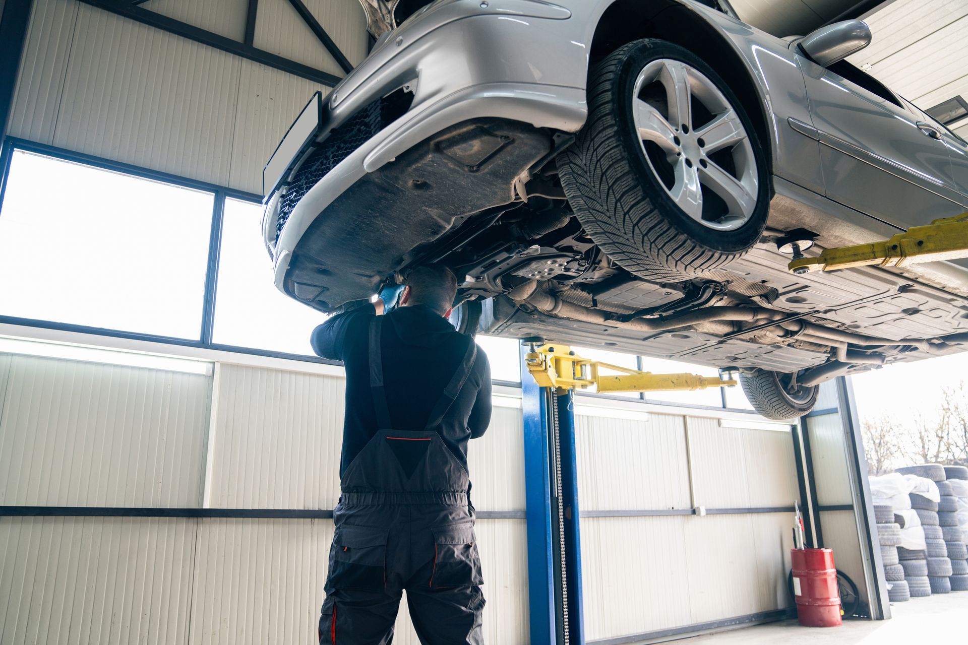 Mechanic working under a car raised on a lift in a garage.