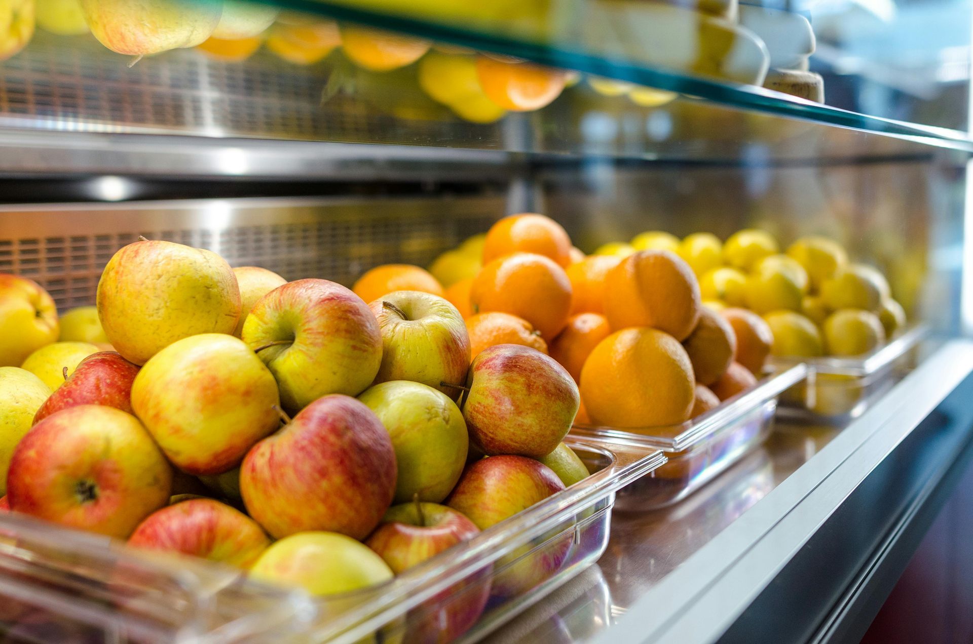 A display case filled with apples , oranges , and lemons.