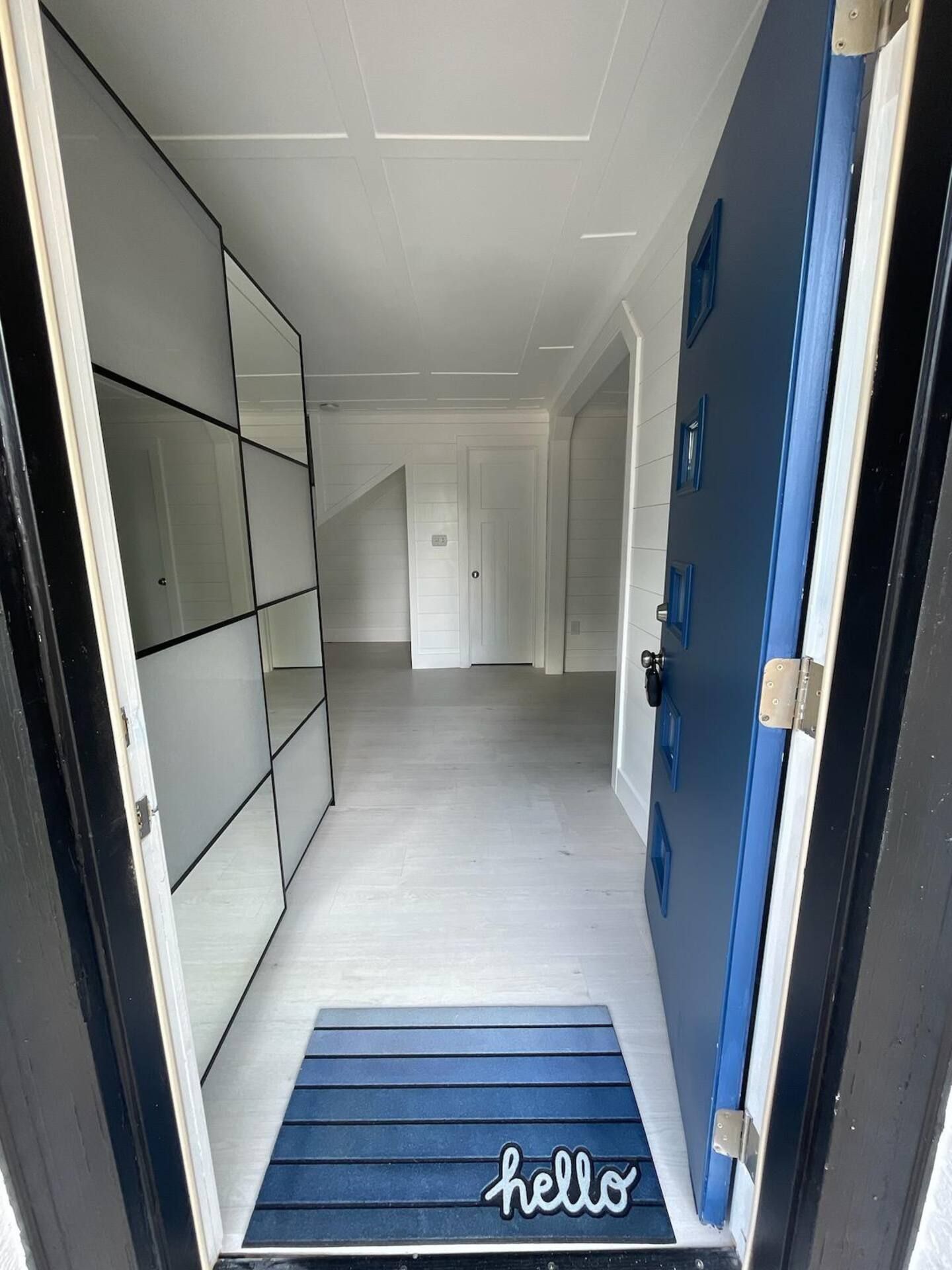 A hallway with a blue door and a blue mat that says `` hello ''.
