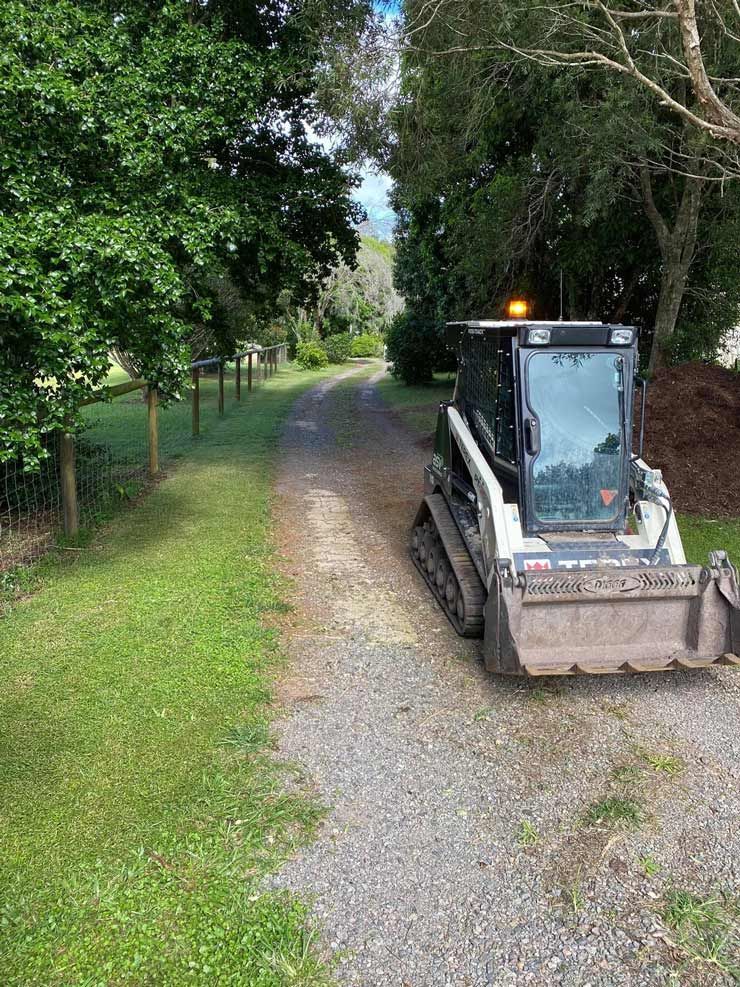 A Bulldozer is Parked on the Side of a Dirt Road — Caloundra Landscape Supplies in Caloundra, QLD