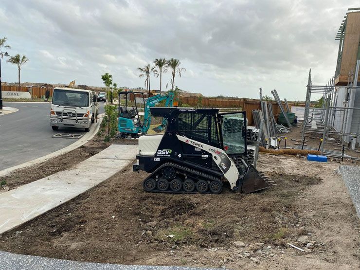 A Bulldozer is Sitting on Top of a Dirt Field Next to a Sidewalk — Caloundra Landscape Supplies in Caloundra, QLD