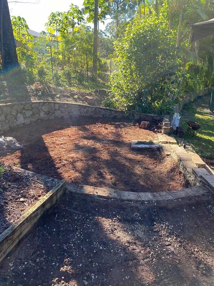 A Dirt Area With a Stone Wall and Trees in the Background — Caloundra Landscape Supplies in Caloundra, QLD