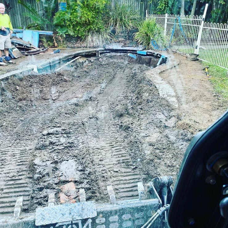 A Man is Standing Next to a Bulldozer in a Muddy Field — Caloundra Landscape Supplies in Caloundra, QLD