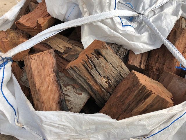 A White Bag Filled With Wood is Sitting on the Ground — Caloundra Landscape Supplies in Beerwah, QLD