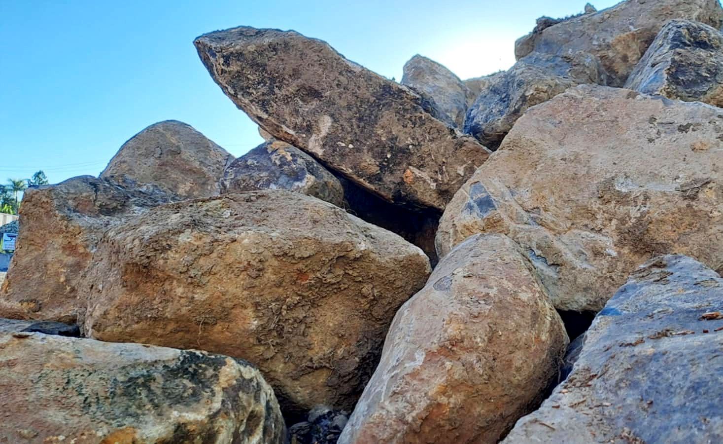 Pile of large, rough, brown rocks against a blue sky.