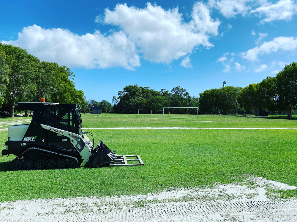 A Bulldozer is Sitting on Top of a Lush Green Field — Caloundra Landscape Supplies in Caloundra, QLD
