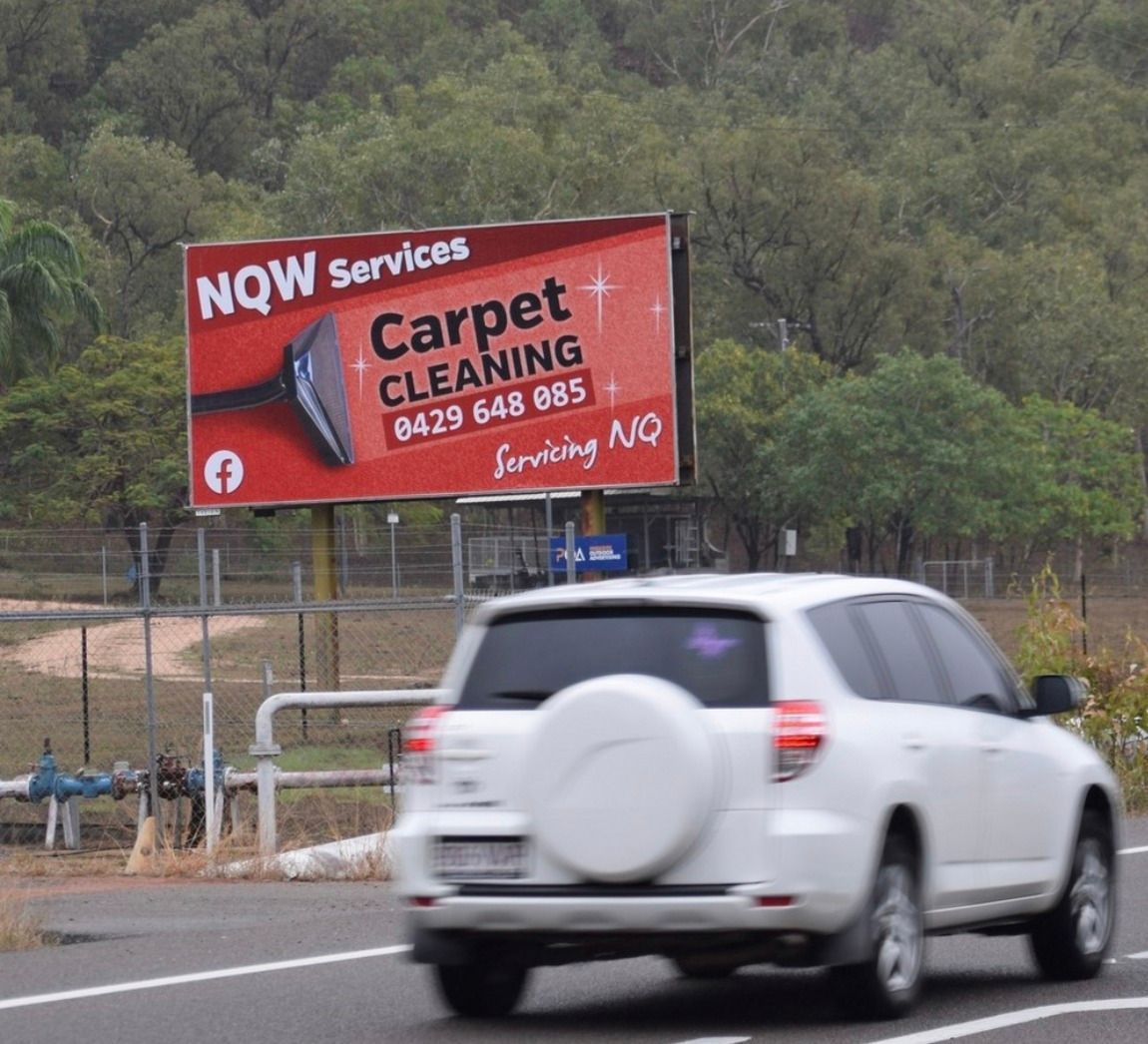 A White Suv is Driving Past a Billboard for Carpet Cleaning — NQW Services In Cardwell, QLD