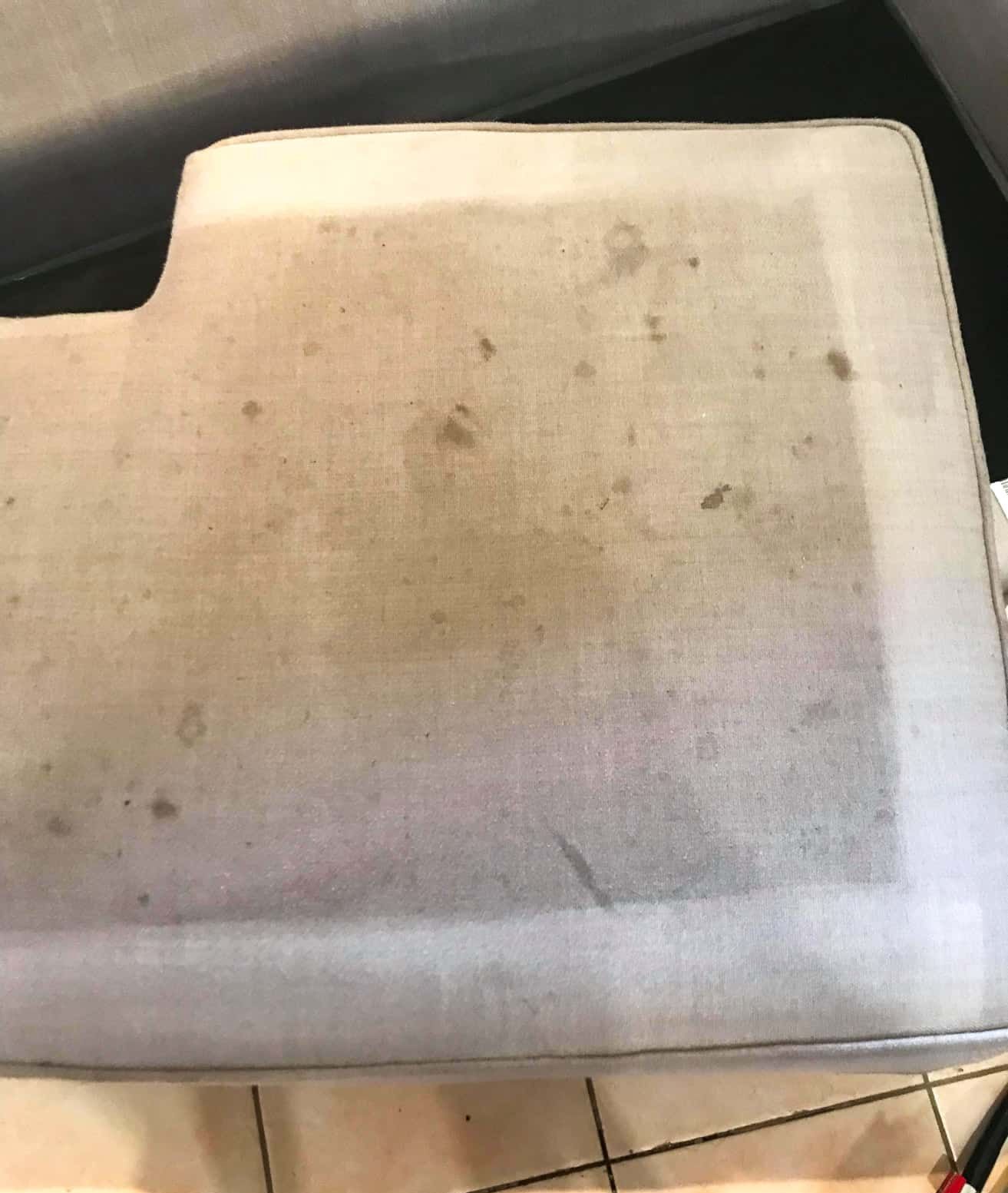 A Dirty Ottoman is Sitting on a Tiled Floor Next to a Couch — NQW Services In Cardwell, QLD