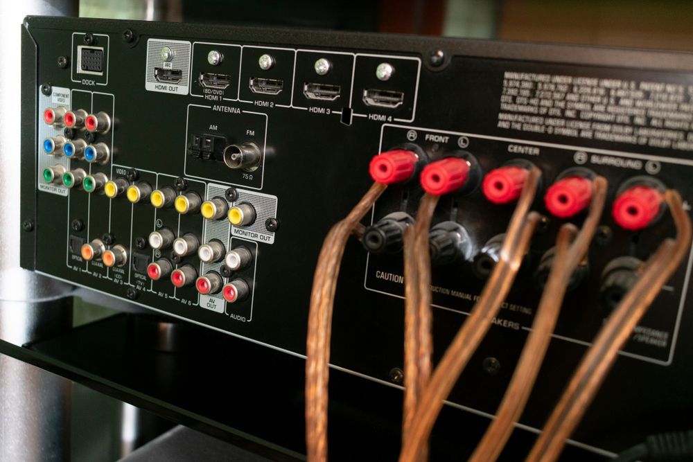 The back of an amplifier with a bunch of wires plugged into it.