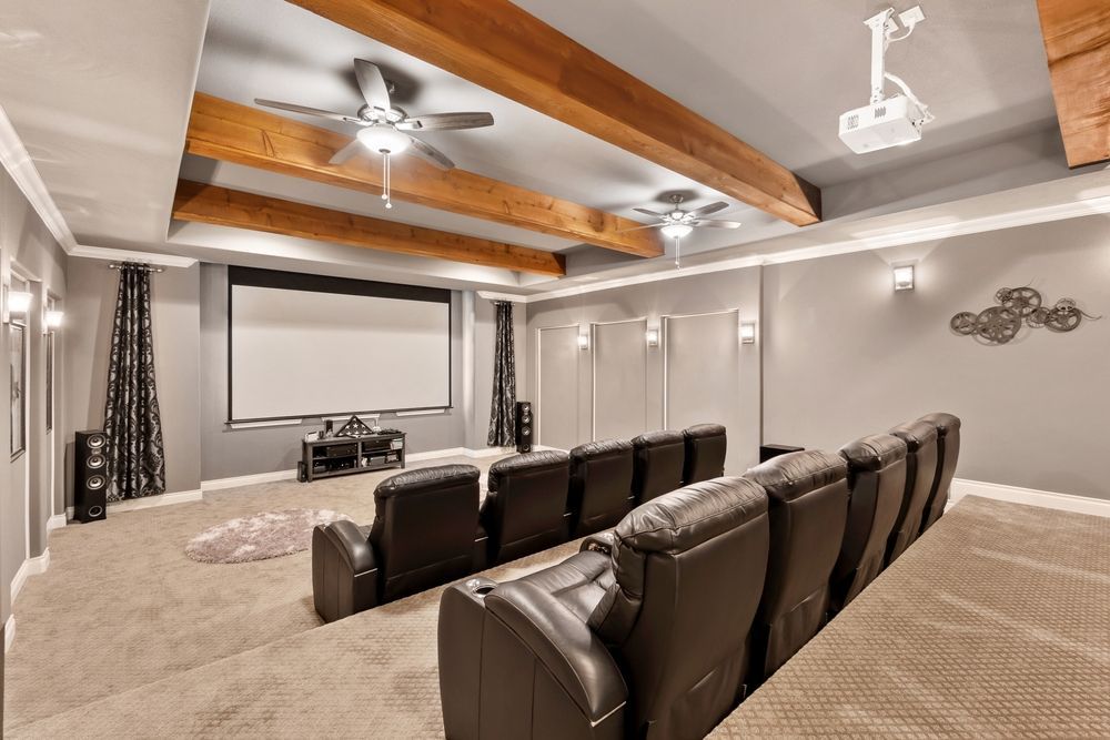 A home theater with a projector screen and a ceiling fan.