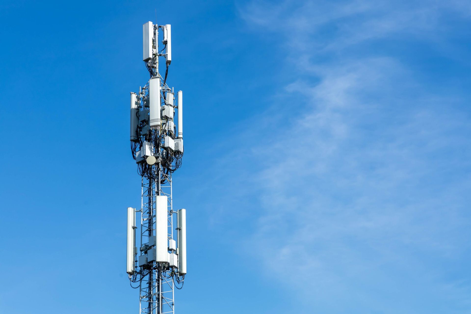 A cell phone tower with antennas against a blue sky.