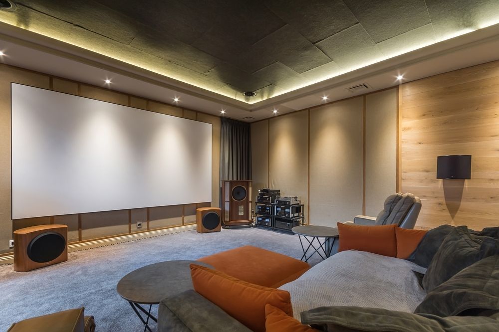 A living room with a couch, chairs, and a large screen.