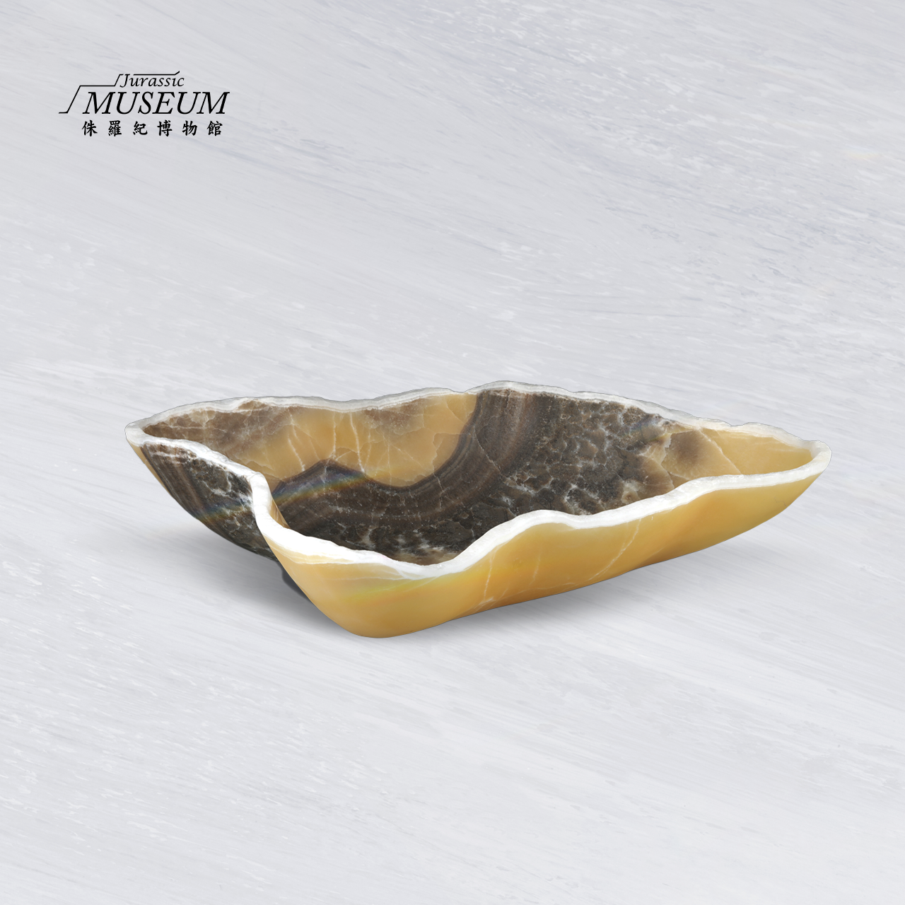 一個淺而形狀不規則的裝飾碗，由條紋狀的半透明金色和深棕色石頭雕刻而成。