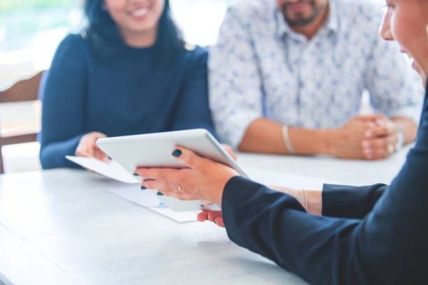 A man and a woman are sitting at a table looking at a tablet.