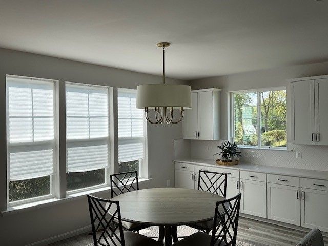 A chandelier is hanging from the ceiling in a room next to a window.