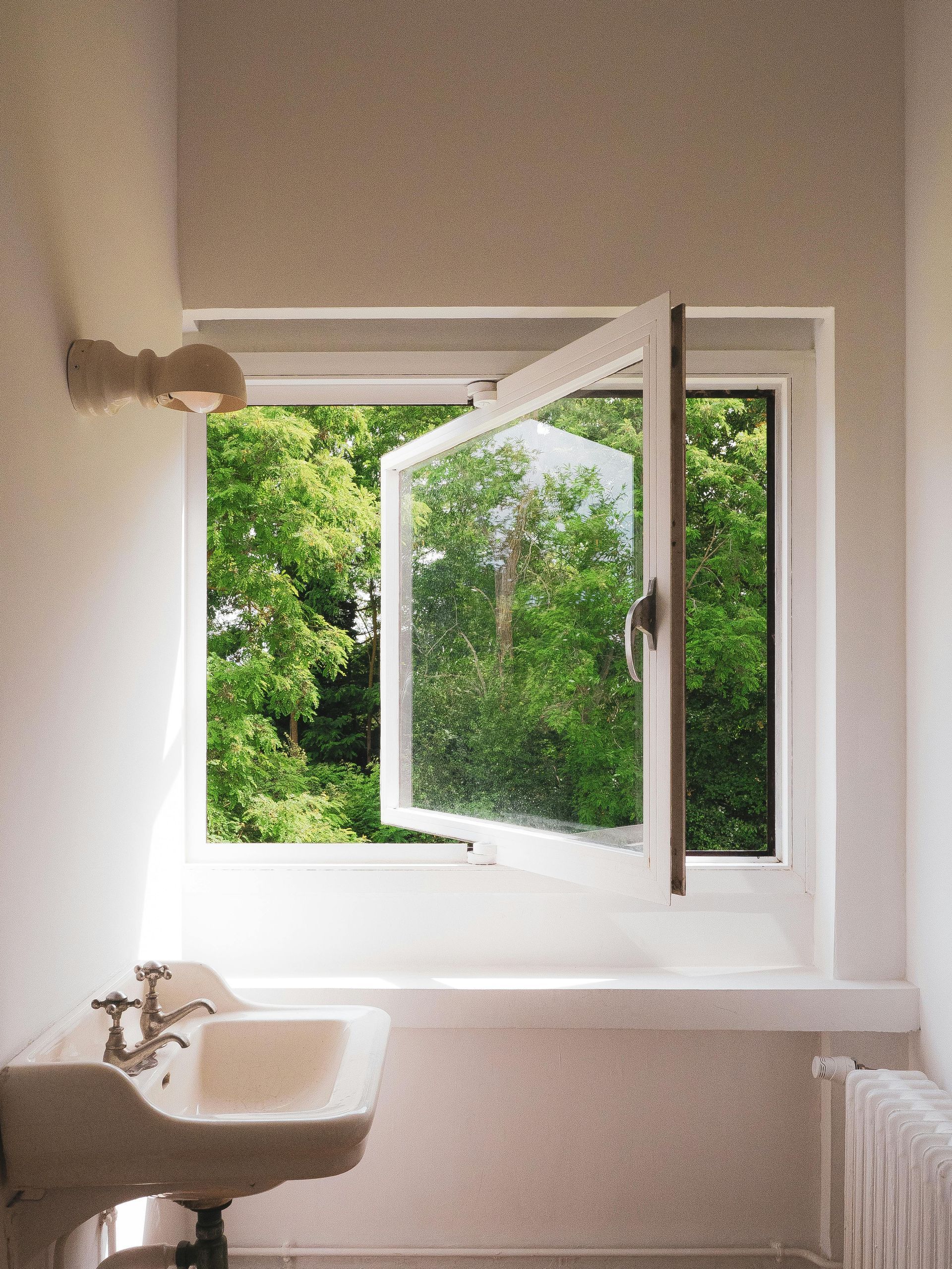 A bathroom with a sink and an open window