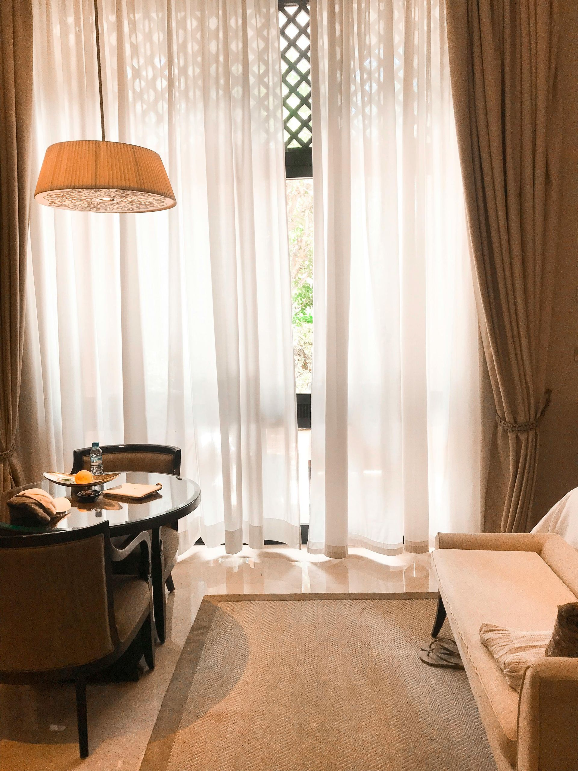 A living room with a couch , table , chairs and curtains.