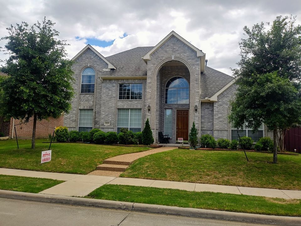 A large brick house with a for sale sign in front of it.
