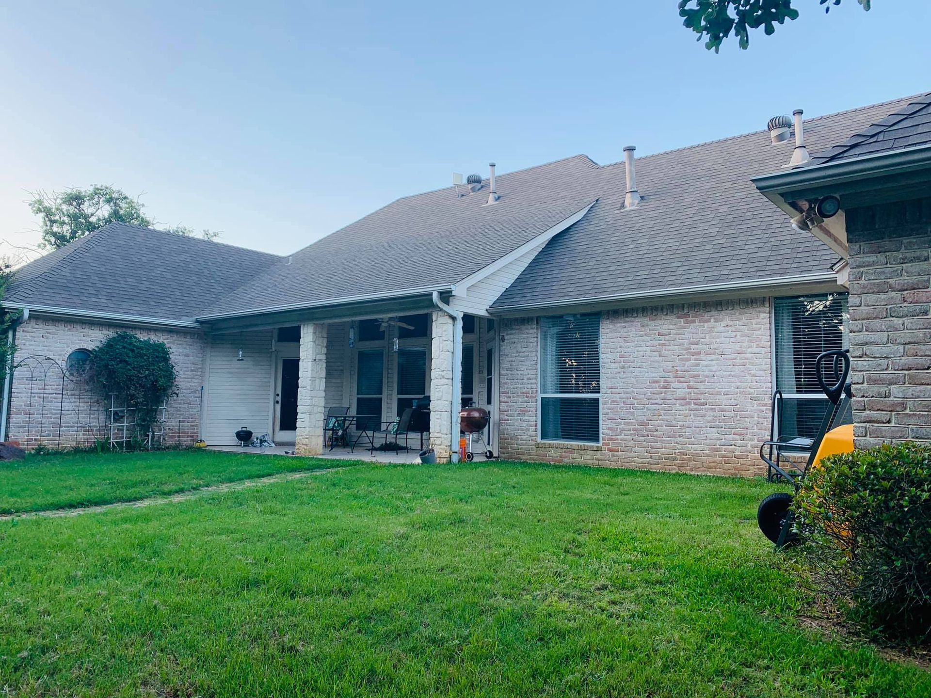 A large brick house with a lush green lawn in front of it.