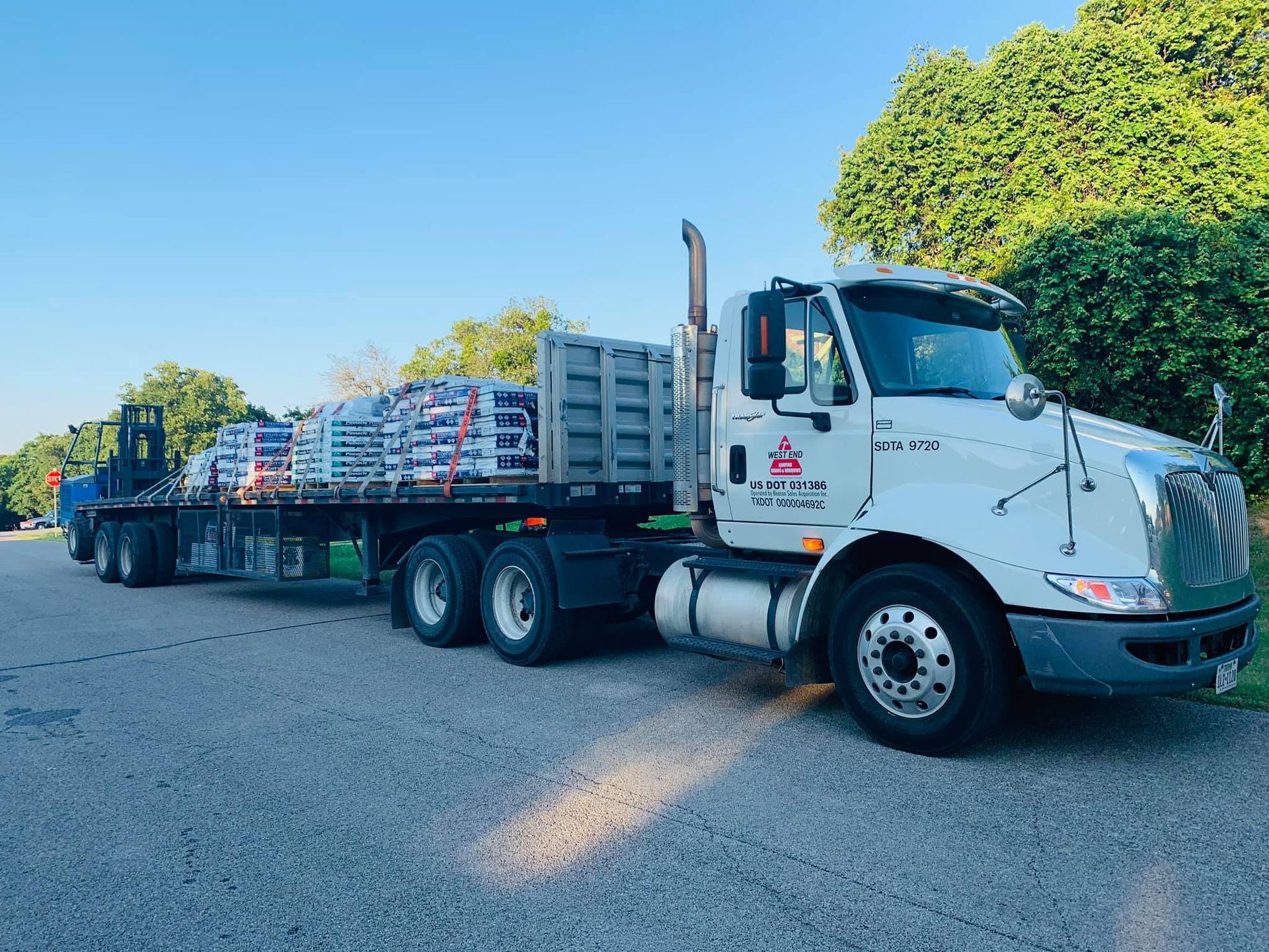A semi truck with a trailer full of pallets is parked on the side of the road.