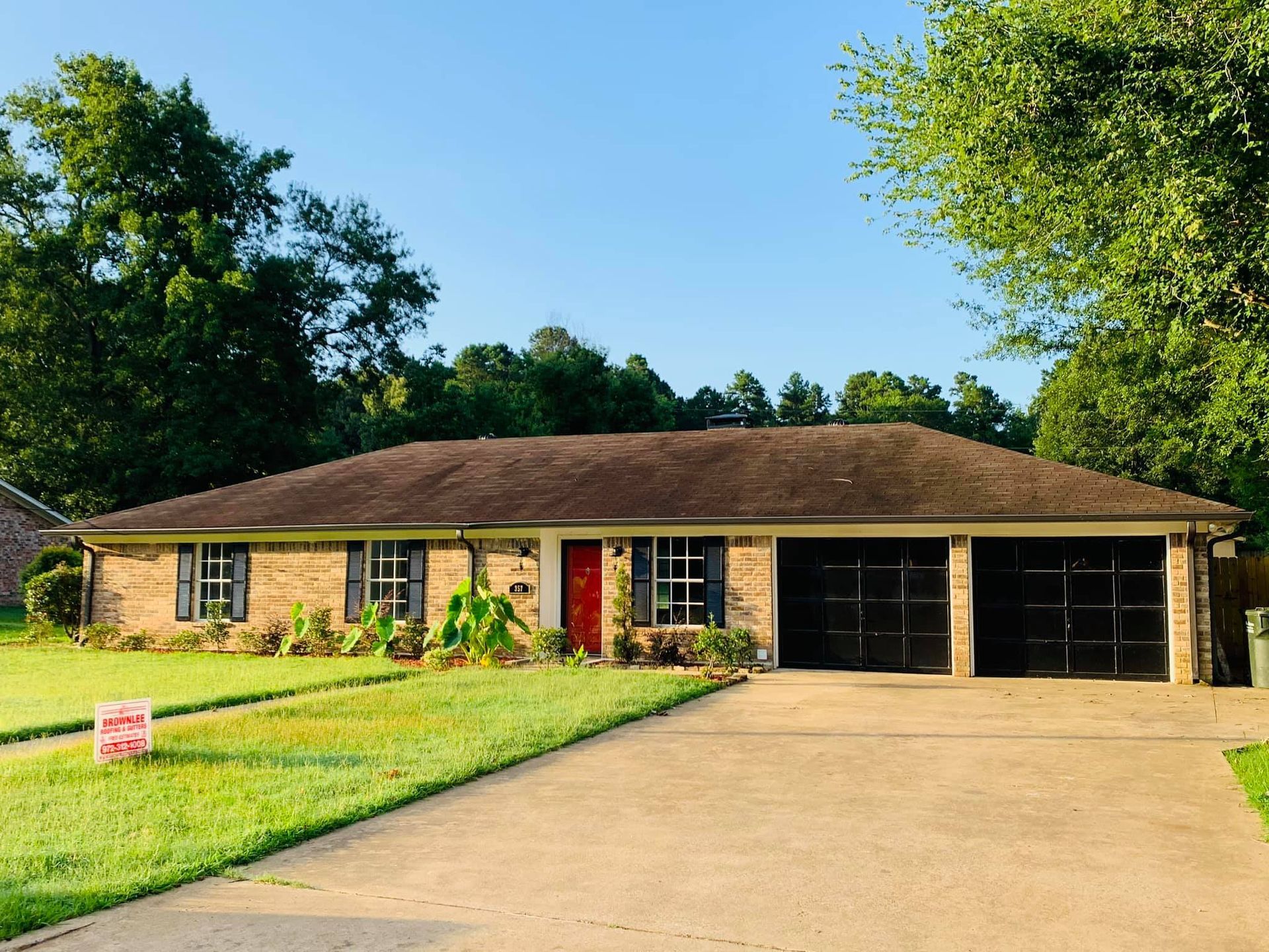 A brick house with two garages and a red door