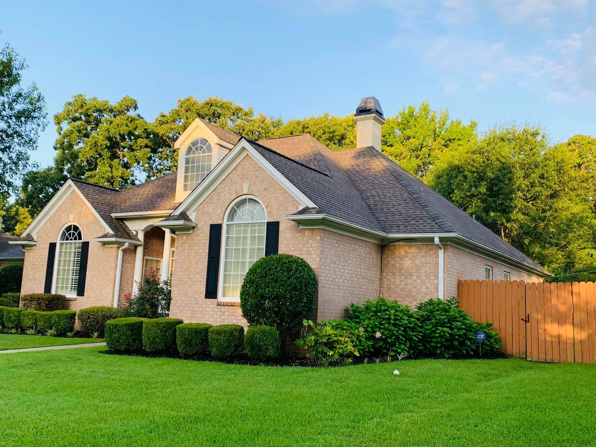A large brick house with a brown roof and black shutters