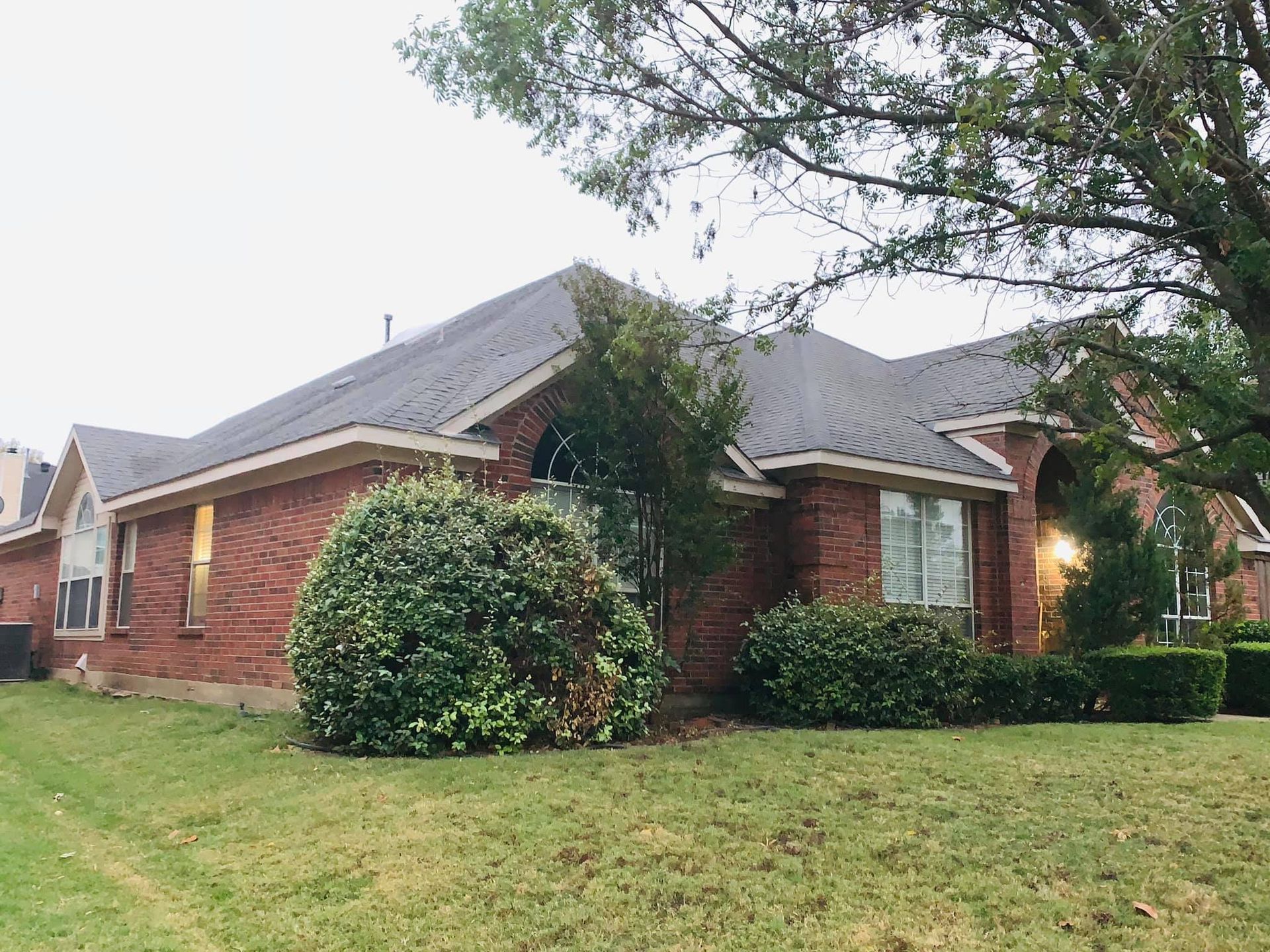 A large brick house with a large lawn in front of it.