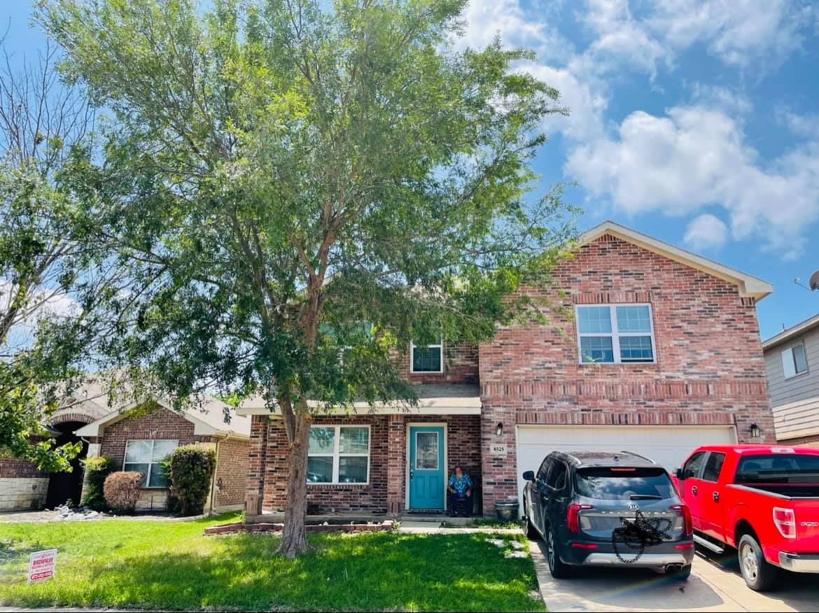 A red truck is parked in front of a brick house.