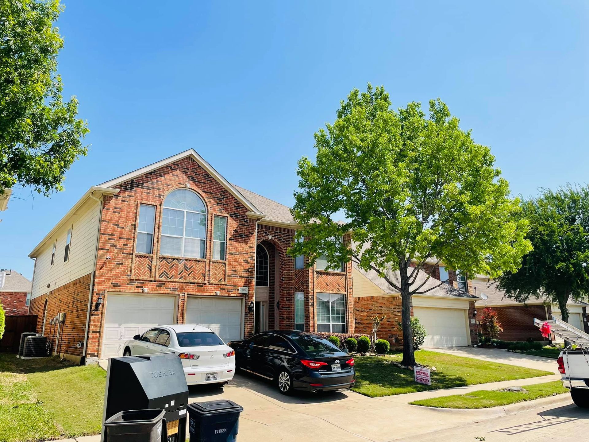 A brick house with two cars parked in front of it.