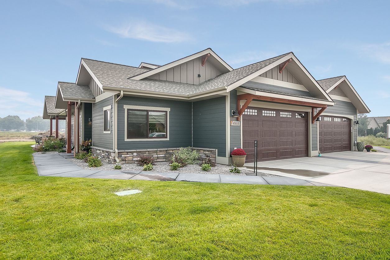 A large house with two garages and a large lawn in front of it.