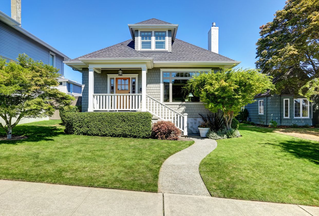 A house with a lush green lawn and a walkway leading to it.