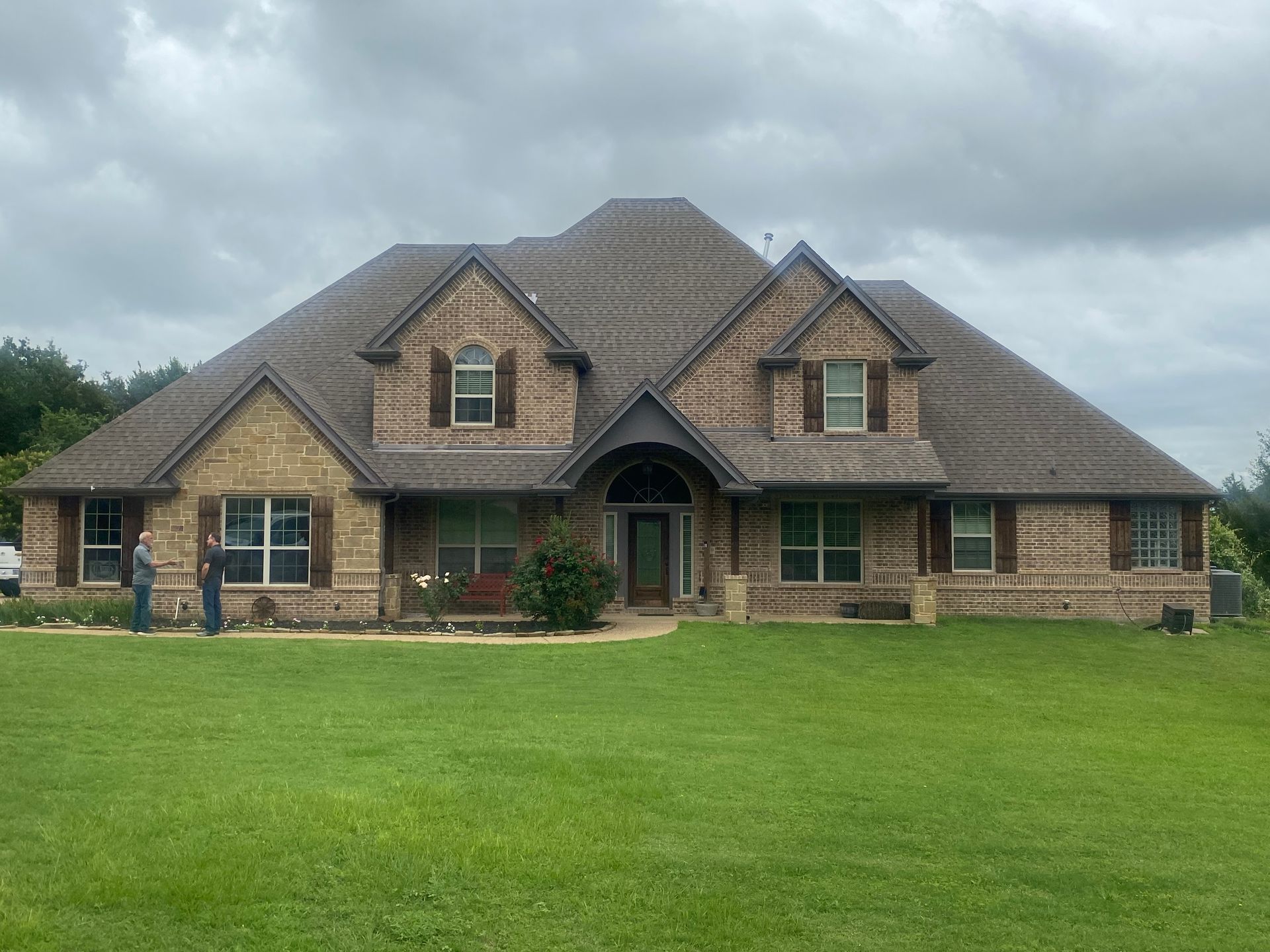 A large brick house with a lush green lawn in front of it.
